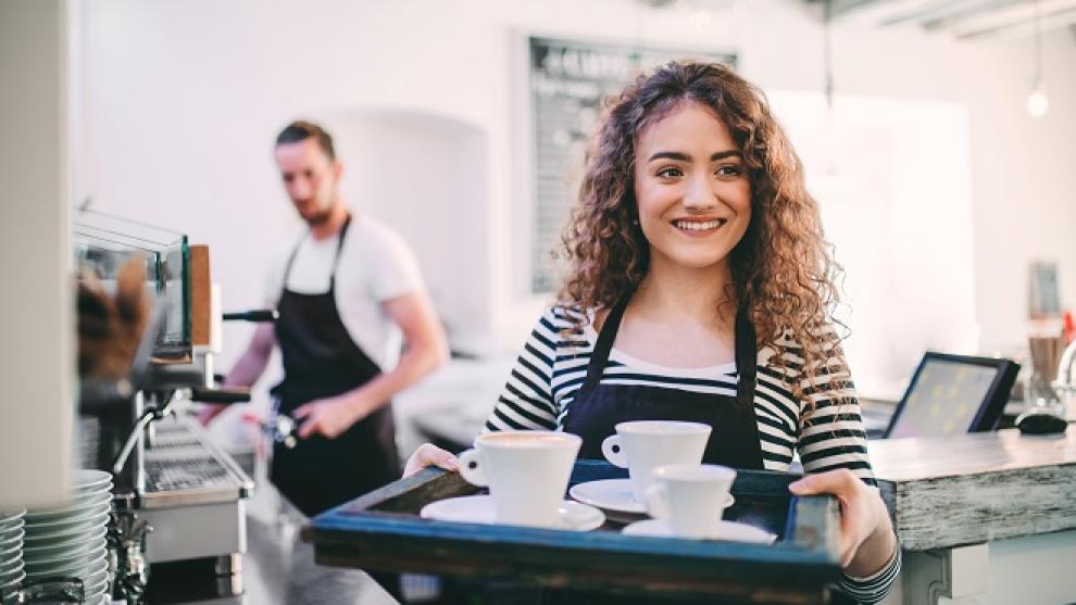 Employee in a coffee shop with a serving tray