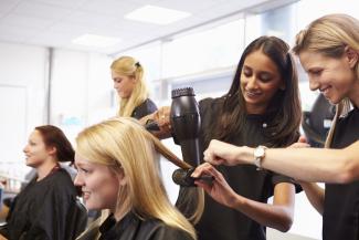 Apprentice hairdresser learning on the job