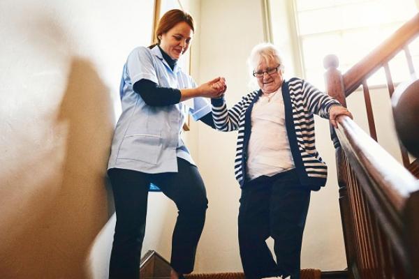 Care worker helping someone walk down the stairs